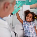 Little girl smiles and high-fives her dentist after using safe dental sedation in Denver, CO